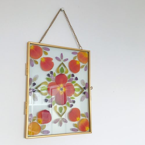 finished DIY crafting project pressed flowers wall art mandala design in gold floating frame transparent glass frame