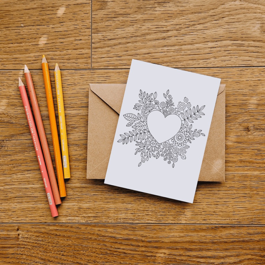 Beautiful coloring page in postcard form, photographed on wooden background with colored pencils and brown envelope. Example of the printable coloring page freebie by Illustrator Anna Grunduls