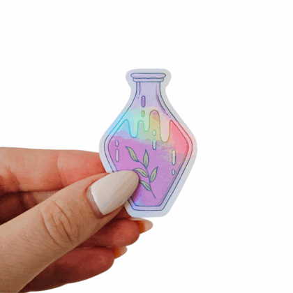 Hand holding a rainbow glow holo sticker shaped like a potion bottle, with leafy green branch design and holographic shimmer. Hand-drawn magical sticker for planners, notebooks, scrapbooks, and creative projects.